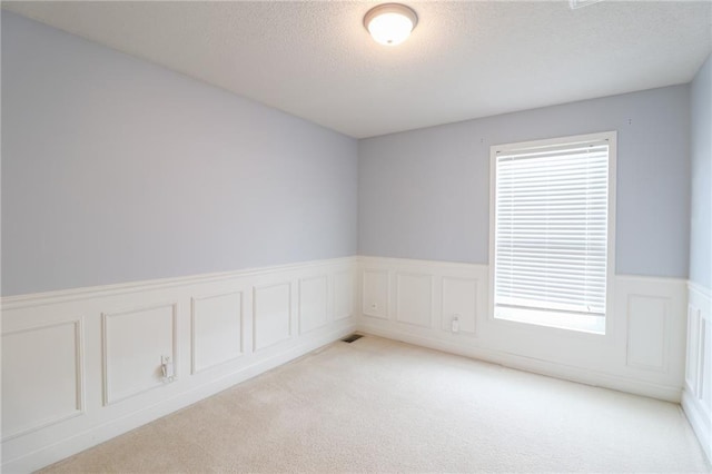 carpeted empty room with a textured ceiling