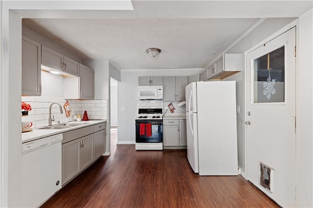 kitchen featuring gray cabinetry, white appliances, dark hardwood / wood-style flooring, sink, and backsplash