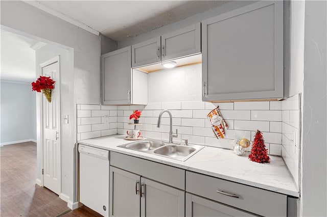 kitchen with white dishwasher, sink, tasteful backsplash, gray cabinetry, and dark wood-type flooring