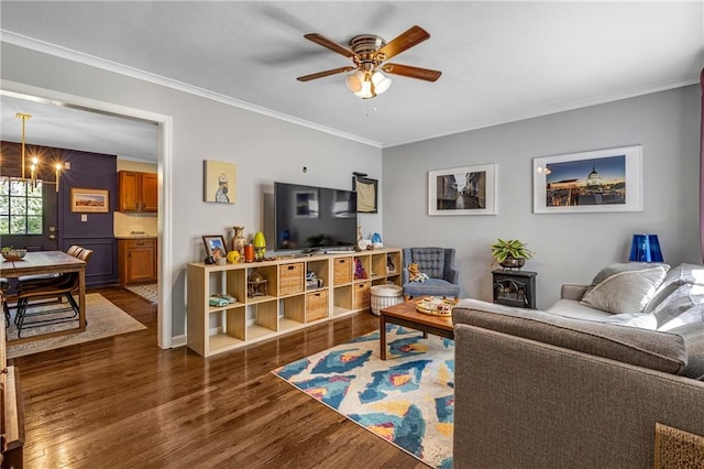 living room featuring dark wood-type flooring, ceiling fan with notable chandelier, and ornamental molding