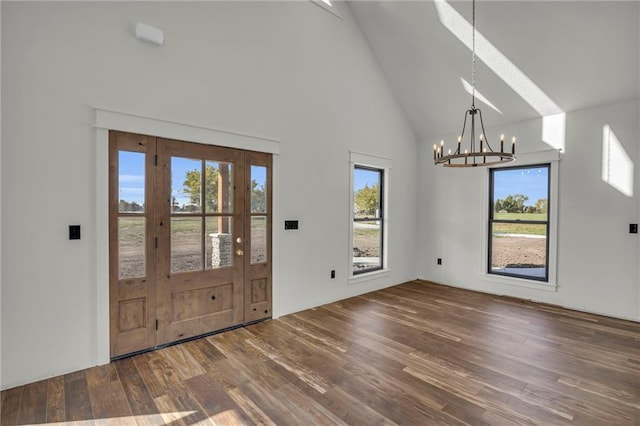 entrance foyer with dark hardwood / wood-style flooring, plenty of natural light, high vaulted ceiling, and a notable chandelier