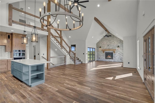 interior space featuring high vaulted ceiling, pendant lighting, and ceiling fan with notable chandelier