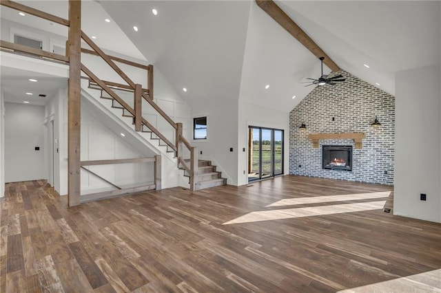 unfurnished living room with ceiling fan, hardwood / wood-style floors, high vaulted ceiling, and beamed ceiling