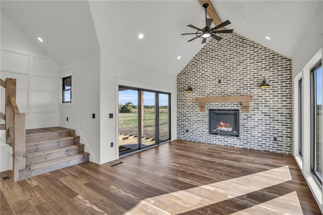 unfurnished living room featuring a large fireplace, high vaulted ceiling, ceiling fan, and dark wood-type flooring