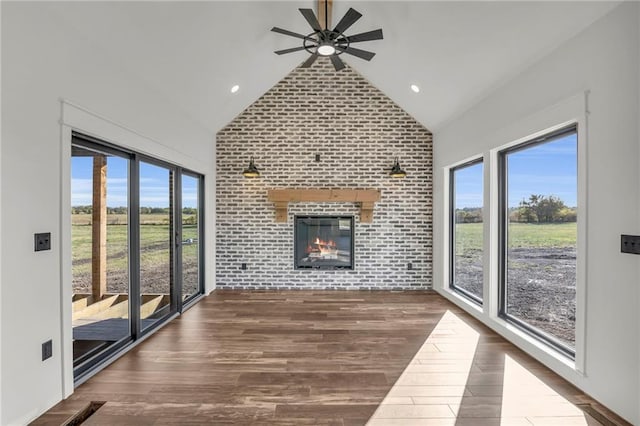 unfurnished living room with a fireplace, dark hardwood / wood-style flooring, brick wall, and lofted ceiling