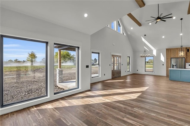 unfurnished living room featuring plenty of natural light, dark hardwood / wood-style floors, beam ceiling, and high vaulted ceiling