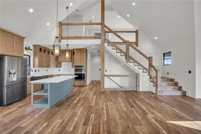 kitchen with pendant lighting, high vaulted ceiling, a center island, and appliances with stainless steel finishes