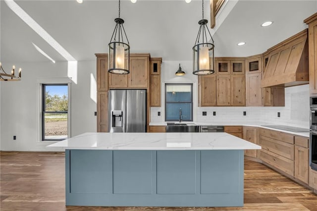 kitchen with light hardwood / wood-style floors, a spacious island, stainless steel appliances, and hanging light fixtures