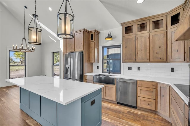 kitchen with stainless steel appliances, light hardwood / wood-style flooring, a chandelier, a kitchen island, and hanging light fixtures