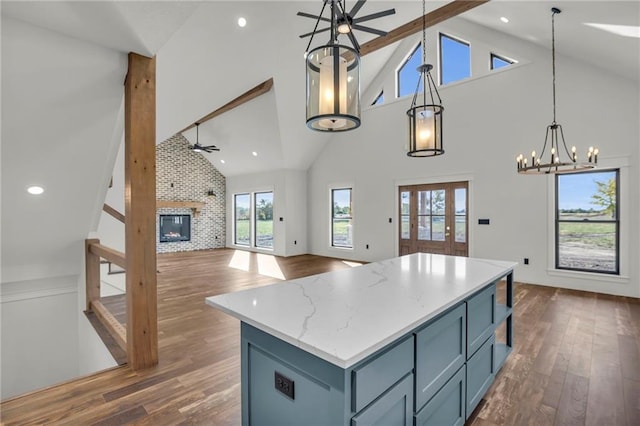 kitchen with ceiling fan with notable chandelier, high vaulted ceiling, dark hardwood / wood-style floors, and decorative light fixtures