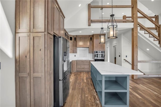 kitchen featuring stainless steel fridge, dark hardwood / wood-style flooring, light stone counters, a center island, and hanging light fixtures