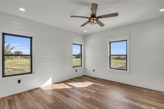 empty room featuring hardwood / wood-style flooring, a wealth of natural light, and ceiling fan