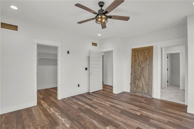 unfurnished bedroom with ceiling fan, dark hardwood / wood-style floors, a walk in closet, and a closet