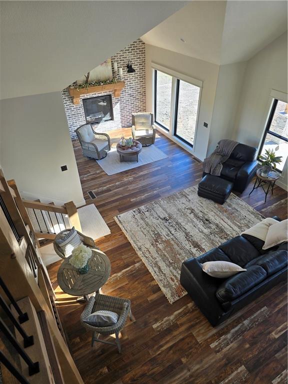 living room with high vaulted ceiling, dark hardwood / wood-style floors, and a brick fireplace