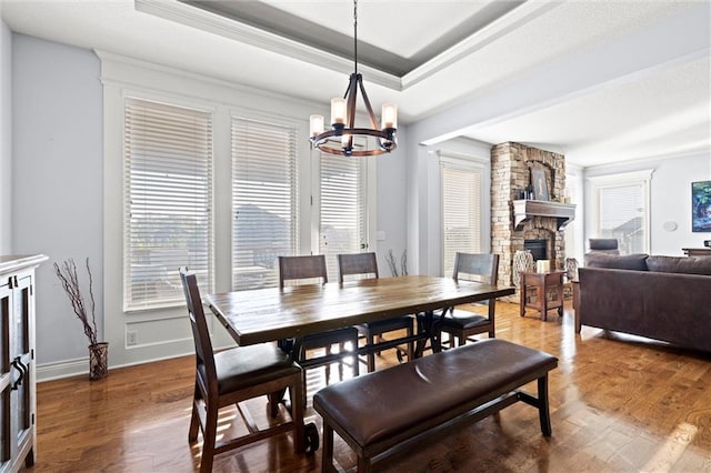 dining area with a notable chandelier, a fireplace, ornamental molding, and dark hardwood / wood-style floors