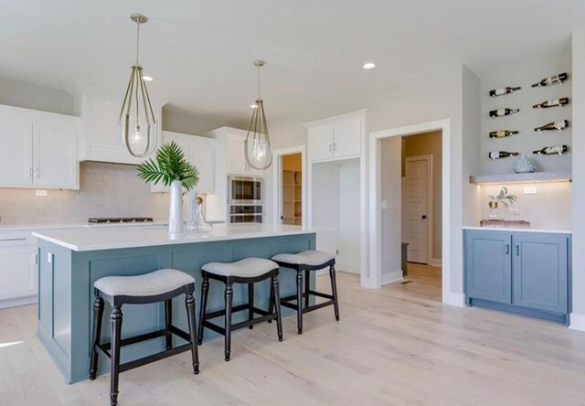 9300 Zarda Dr, Lenexa, KS 66227 - kitchen featuring stainless steel microwave, tasteful backsplash, light wood-style flooring, and white cabinets