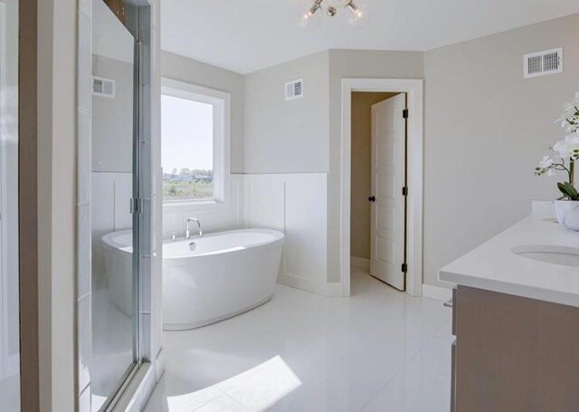 bathroom featuring visible vents, a freestanding bath, double vanity, and a sink