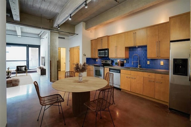 kitchen with sink, light brown cabinets, track lighting, decorative backsplash, and appliances with stainless steel finishes