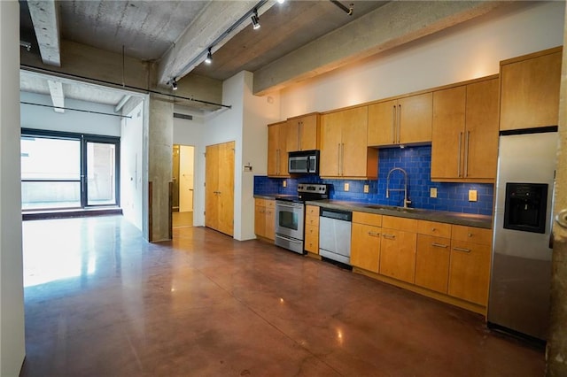 kitchen featuring rail lighting, stainless steel appliances, tasteful backsplash, and sink