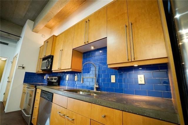 kitchen featuring stainless steel appliances, tasteful backsplash, dark stone counters, and sink