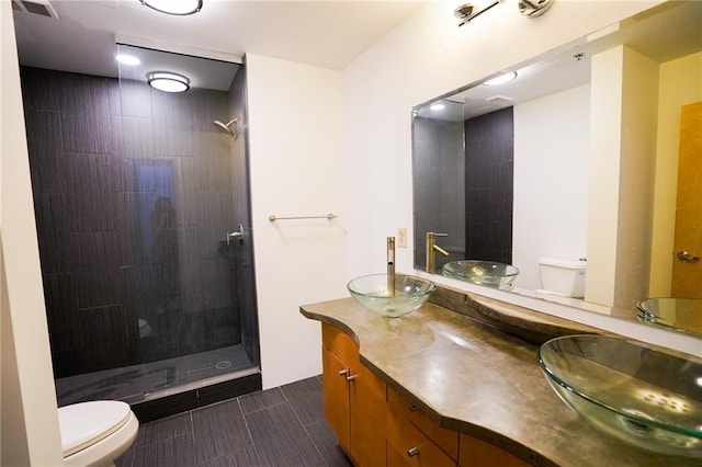 bathroom with tiled shower, tile patterned floors, vanity, and toilet