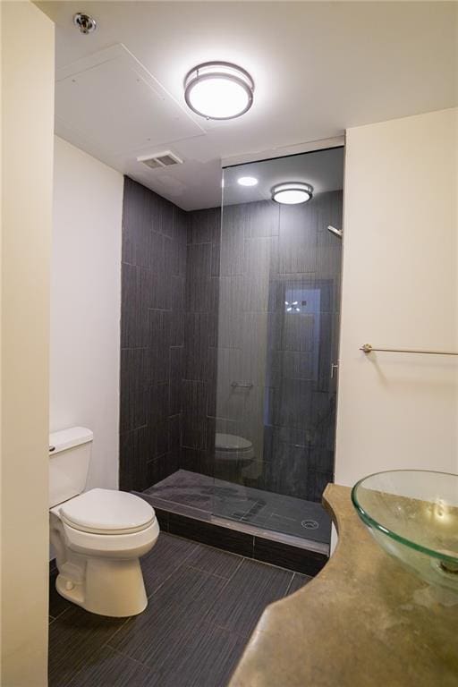 bathroom with tiled shower, tile patterned flooring, and toilet