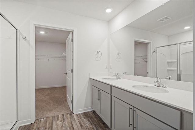 bathroom with hardwood / wood-style floors, vanity, and a shower with shower door