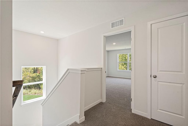 hallway featuring dark colored carpet