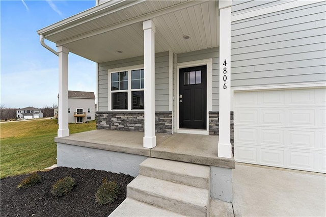 doorway to property featuring a lawn, a porch, and a garage