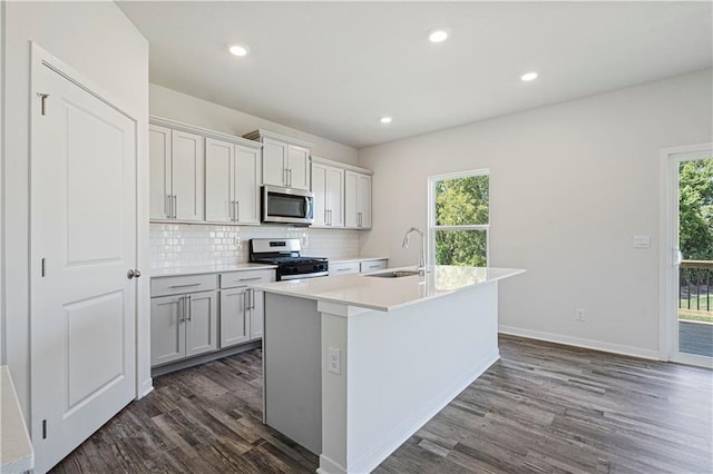 kitchen featuring a wealth of natural light, stainless steel appliances, a kitchen island with sink, and sink