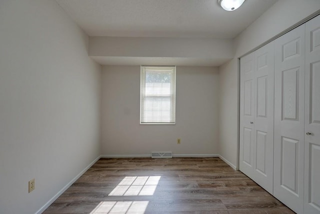 unfurnished bedroom featuring light hardwood / wood-style flooring and a closet