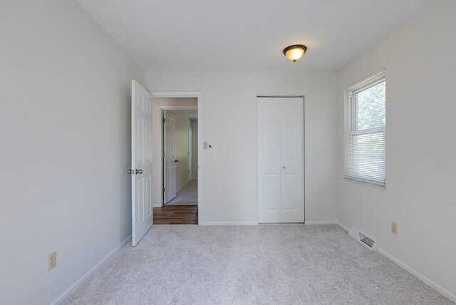 unfurnished bedroom featuring light carpet and a closet