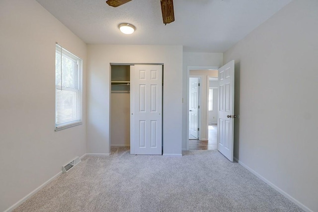 unfurnished bedroom with light carpet, a closet, and ceiling fan