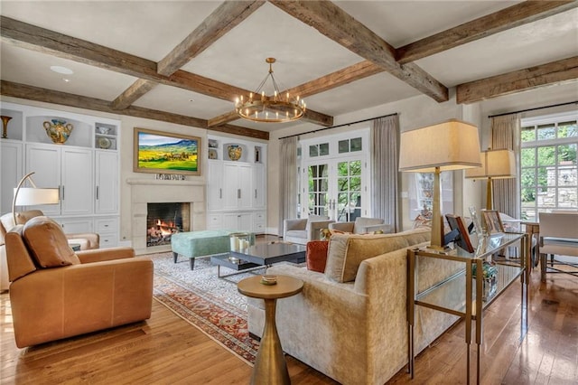 living room featuring beam ceiling, a notable chandelier, a wealth of natural light, and hardwood / wood-style floors