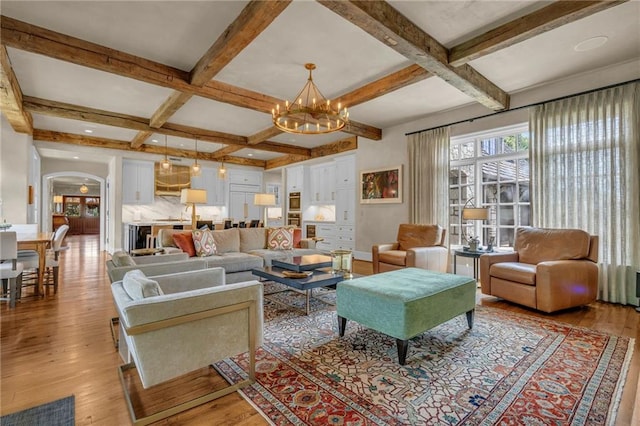 living room featuring coffered ceiling, light hardwood / wood-style floors, a notable chandelier, and beam ceiling