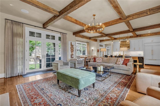 living room featuring coffered ceiling, french doors, beam ceiling, a notable chandelier, and light wood-type flooring