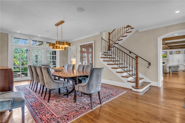 dining room featuring beam ceiling, ornamental molding, and light wood-type flooring