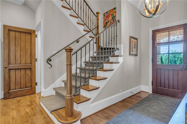 foyer with a chandelier, light wood-type flooring, and vaulted ceiling