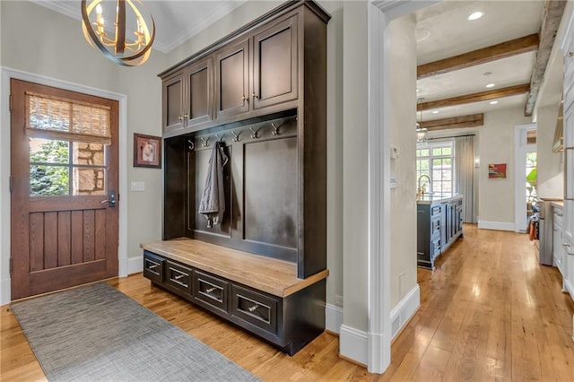 mudroom with an inviting chandelier, light wood-type flooring, beamed ceiling, crown molding, and sink