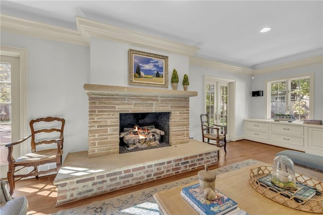 living room with light hardwood / wood-style flooring, crown molding, and a brick fireplace