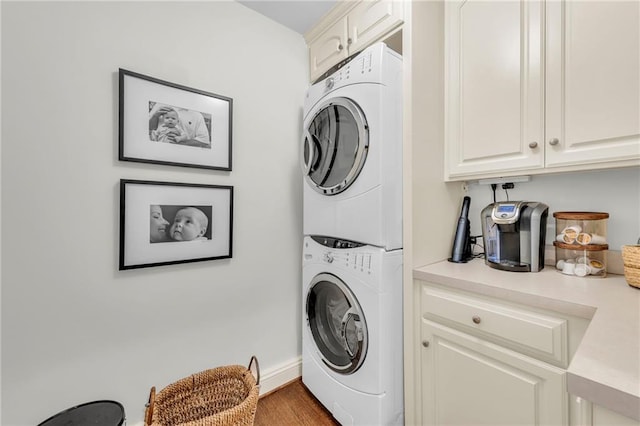 laundry area with stacked washer / drying machine, wood-type flooring, and cabinets