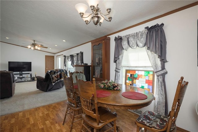 dining room with lofted ceiling, ceiling fan with notable chandelier, hardwood / wood-style floors, and a textured ceiling