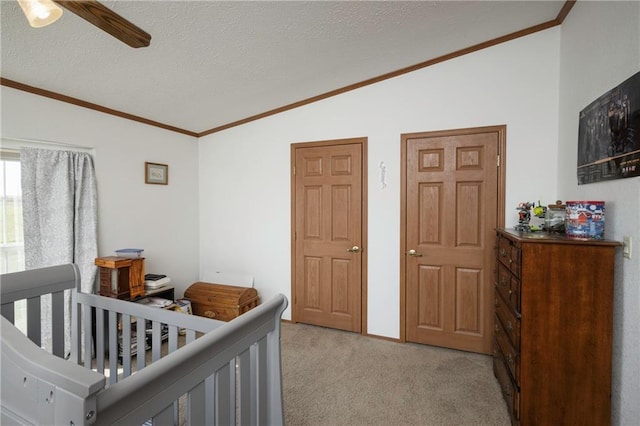 bedroom with ceiling fan, light carpet, a crib, vaulted ceiling, and a textured ceiling