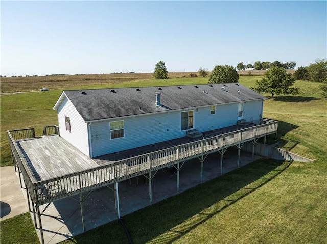 rear view of house featuring a rural view, a wooden deck, and a lawn