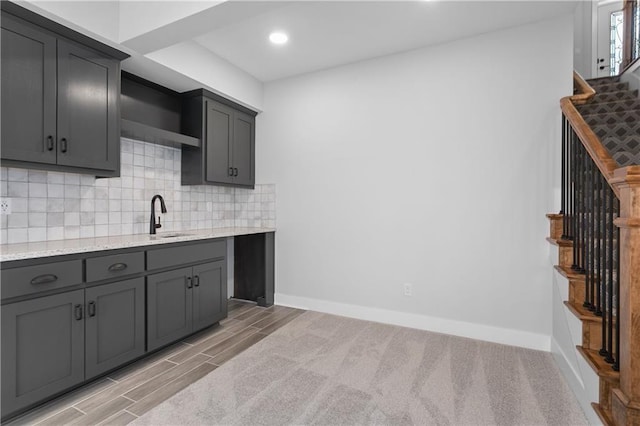 kitchen featuring light stone counters, light hardwood / wood-style floors, tasteful backsplash, and gray cabinetry