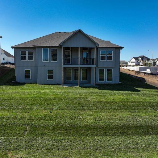 rear view of property featuring a balcony and a lawn