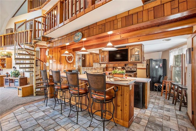 kitchen featuring black fridge, a kitchen island, beam ceiling, and hanging light fixtures