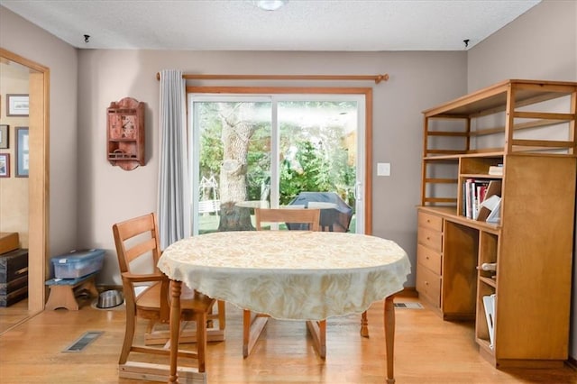 dining area with a textured ceiling and light wood-type flooring