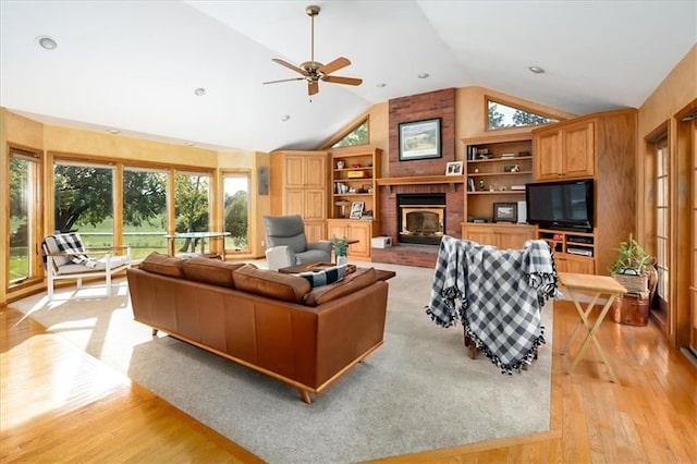 living room featuring light hardwood / wood-style flooring, a wealth of natural light, a fireplace, and ceiling fan