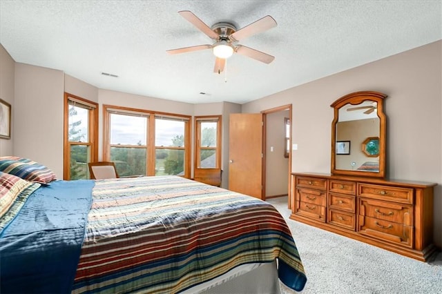 bedroom featuring ceiling fan, light carpet, and a textured ceiling